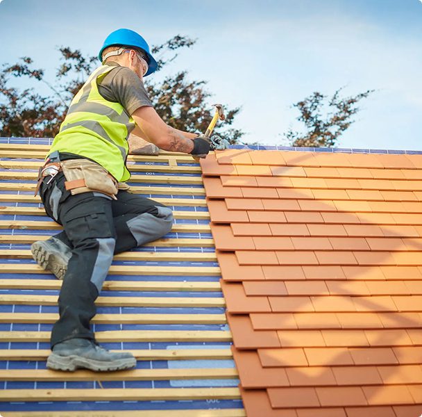 Roofer installing tiles on house roof.